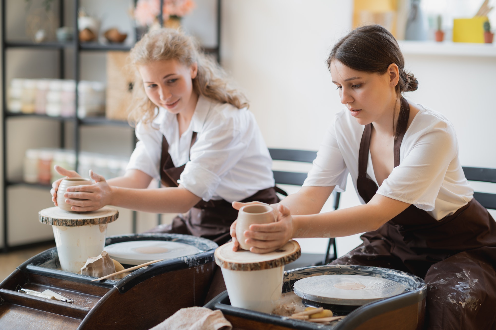 overview-of-two-young-potters-by-pottery-wheels-while-preparing-ceramic-pots-from-raw-clay.jpg
